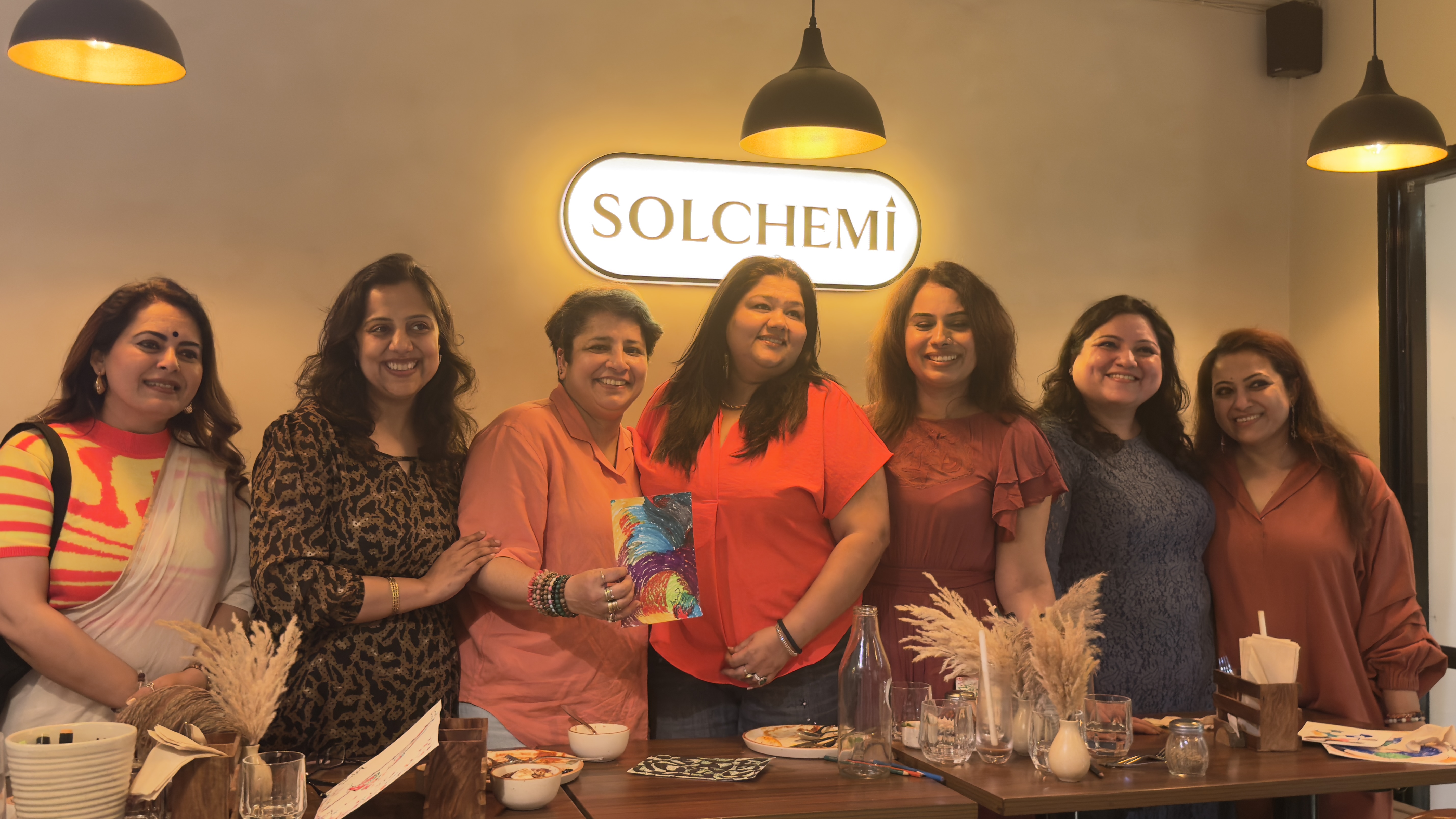 Guests at Solchemi cafe Shahpur Jat — art event with the Solchemi sign